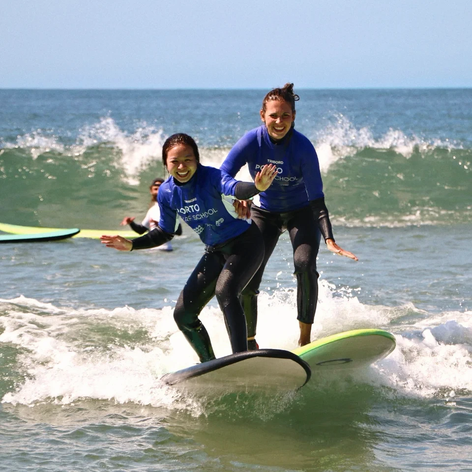 Porto Surf School – Girls having fun surfing small waves in Porto