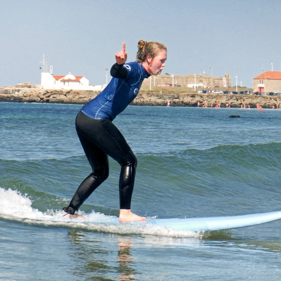 Porto Surf School – Girl having fun surfing small waves in Porto
